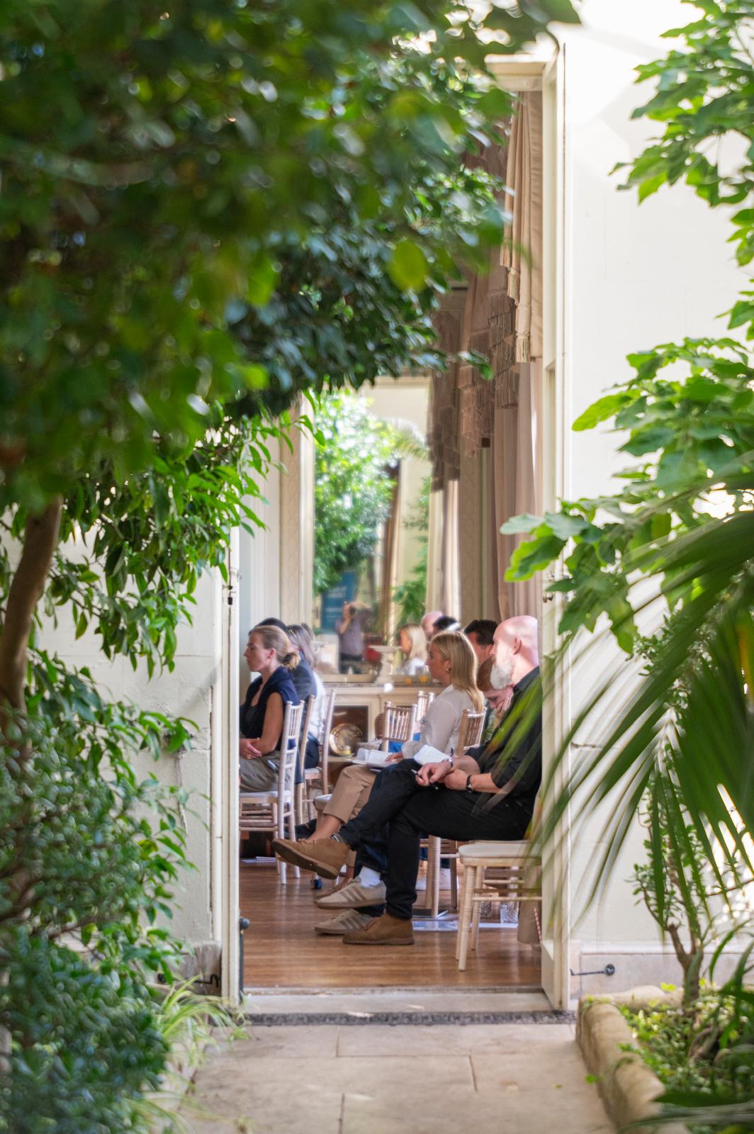 Beacon Voices listening to a session at Illuminate 2026, seen through the conservatory at Prestwold Hall